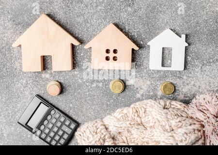 Figure di casa, calcolatrice, soldi e cappello caldo sul tavolo. Concetto di stagione di riscaldamento Foto Stock