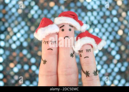 L'arte delle dita della famiglia dispiaciuta celebra il Natale. Concetto di gruppo di persone tristi nei cappelli di nuovo anno. Foto Stock