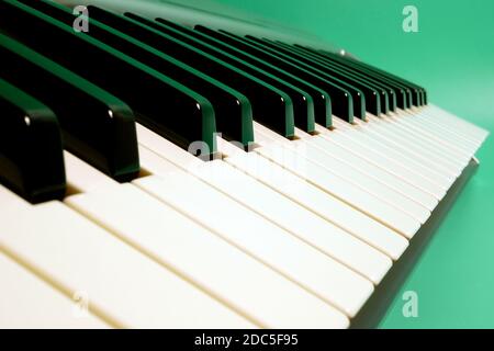 Primo piano del sintetizzatore musicale a tastiera su sfondo turchese. Mettere a fuoco la terra centrale. Foto Stock