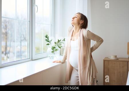 Assistenza sanitaria, trattamento. Giovane donna incinta che sente dolore improvviso alla schiena. Futura mamma che soffre di mal di schiena. Foto Stock