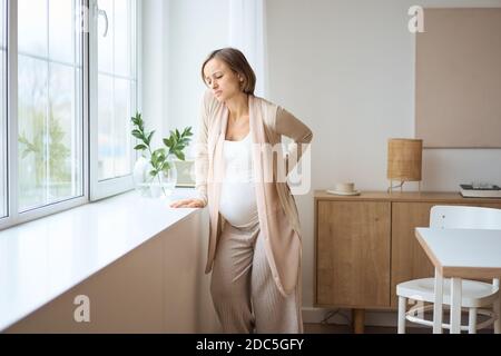 Assistenza sanitaria, trattamento. Giovane donna incinta che sente dolore improvviso alla schiena. Futura mamma che soffre di mal di schiena. Foto Stock