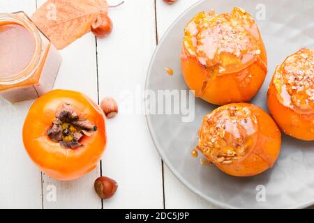 Il persimmon ripieno di granola e salsa al caramello. Il persimone al forno. Foto Stock