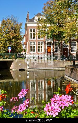 Tipica scena dei canali olandesi con la tradizionale casa olandese con tegole, biciclette e fiori colorati. Foto Stock
