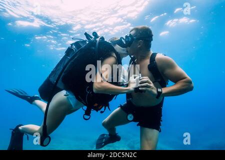 20 agosto 2020. Anapa, Russia. Felice coppia di subacquei baciare sott'acqua in mare blu trasparente. Immersioni subacquee in oceano Foto Stock