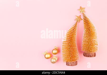 Natale sfondo luminoso e delicato con decorazioni in oro con glitter, alberi di natale, stelle su elegante sfondo rosa pastello, vista dall'alto. Foto Stock