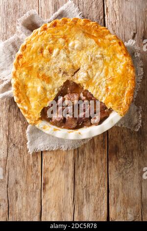 Deliziosa torta di bistecca inglese tradizionale da primo piano in una teglia sul tavolo. Vista dall'alto verticale Foto Stock