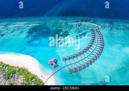 Incredibile paesaggio aereo, Maldive isola, resort di lusso ville d'acqua e molo in legno. Bella cielo e nuvole e spiaggia, vacanza estiva Foto Stock