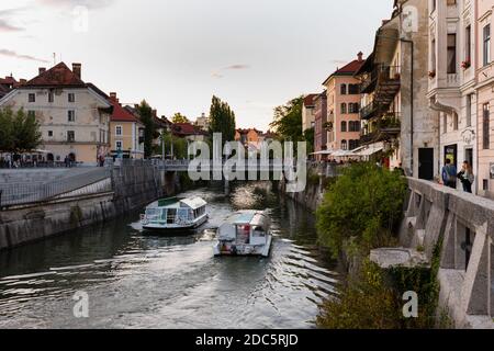 La passeggiata sul fiume Lubibljanica nella capitale slovena Città di Lubiana con il ponte di Cobblers e barche turistiche giornata di sole in estate con Foto Stock
