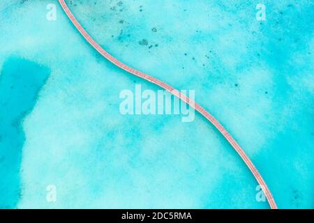 Vista aerea esotica delle acque turchesi con molo in legno nelle isole Maldive. Incredibile laguna di mare. Acque tropicali dell'oceano, tempo soleggiato, aereo astratto Foto Stock