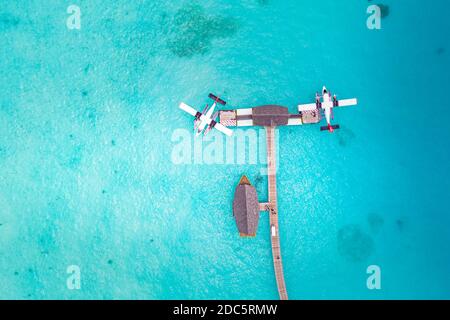 Splendida vista aerea del molo Maldive idrovolante vista dall'alto con barca in legno Dhoni e spiaggia tropicale, molo su meraviglioso mare blu. Viaggi di lusso Foto Stock