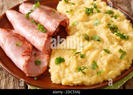 Dividere il porridge di Pea con prosciutto fritto e prezzemolo primo piano in un piatto sul tavolo. Orizzontale Foto Stock