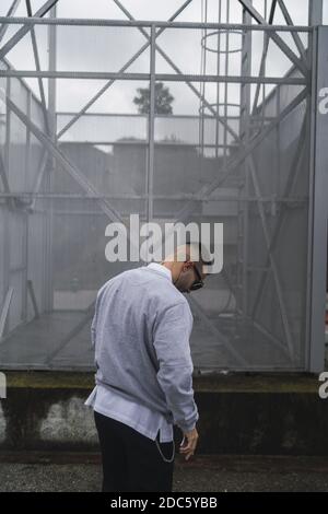 Un'immagine verticale di un giovane elegante e attraente uomo che indossa un maglione sopra una camicia Foto Stock