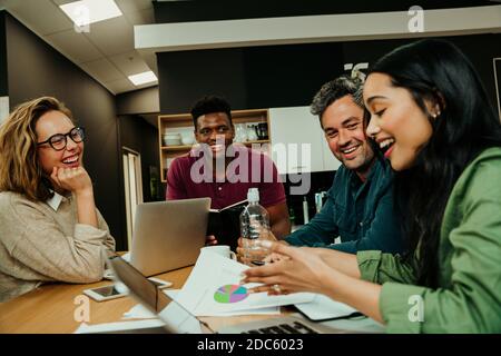 Gruppo di uomini d'affari che si incontrano nell'atrio dell'ufficio tra una riunione e l'altra una pausa pranzo che parla di idee per un nuovo progetto Foto Stock