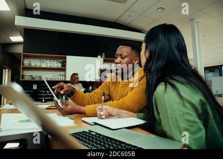 Idee di brainstorming maschili di razza mista con imprenditore femminile seduto dentro atrio dell'ufficio durante la pausa pranzo Foto Stock