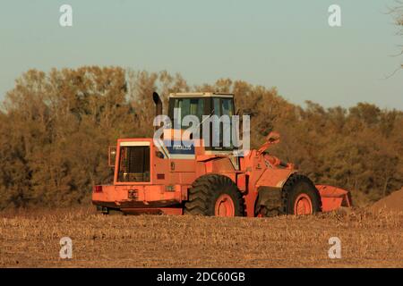 Un caricatore frontale Fiatallis Heavy Equipment in un campo agricolo pronto per lavorare con cielo blu e alberi nel paese in Kansas in un giorno di autunno. Foto Stock