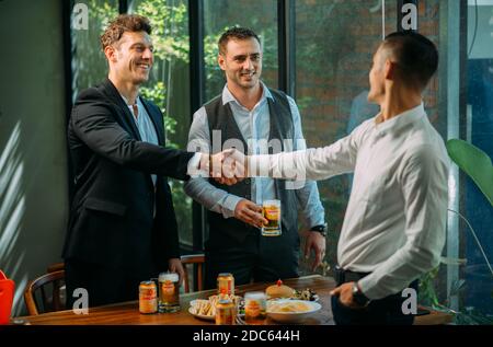 Gli uomini d'affari bevono birra Ganzberg, parlano e ridono mentre si riposano al pub Foto Stock