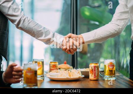 Gli uomini d'affari bevono birra Ganzberg, parlano e ridono mentre si riposano al pub Foto Stock