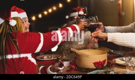 Felici amici anziani multirazziali che tostano con bicchieri di vino rosso durante Festa di Natale cena celebrazione sul patio casa festa Foto Stock