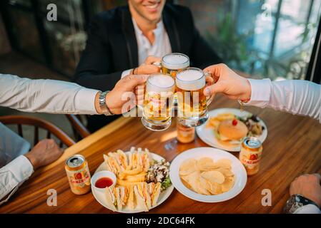 Gli uomini d'affari bevono birra Ganzberg, parlano e ridono mentre si riposano al pub Foto Stock