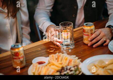 Gli uomini d'affari bevono birra Ganzberg, parlano e ridono mentre si riposano al pub Foto Stock