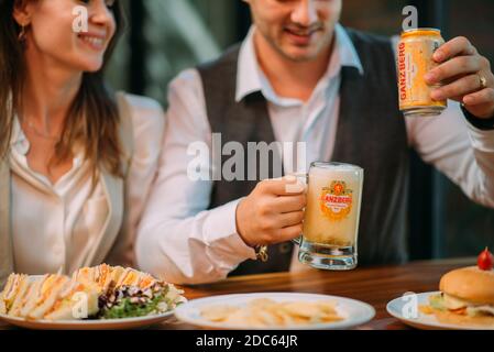 Gli uomini d'affari bevono birra Ganzberg, parlano e ridono mentre si riposano al pub Foto Stock