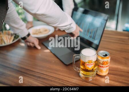 Gli uomini d'affari bevono birra Ganzberg, parlano e ridono mentre si riposano al pub Foto Stock