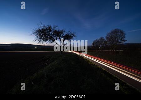 Sentieri leggeri dalle auto di notte su una strada di campagna In Germania Foto Stock