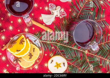 Due tazze di vino caldo o di gluhwein con cannella, spezie e fette d'arancia su sfondo rosso di Natale vista dall'alto. Bevanda tradizionale durante la vacanza invernale. vin brulé Foto Stock