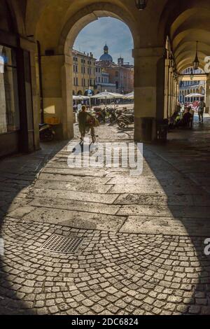 Vista del ciclista e Piazza delle Erbe attraverso archi e cupola del Duomo di Padova visibile, Padova, Veneto, Italia Foto Stock