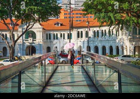 Una donna con ombrello come protezione contro il sole cammina verso il Singapore Art Museum (SAM), situato nella costruzione di una ex scuola cattolica Foto Stock