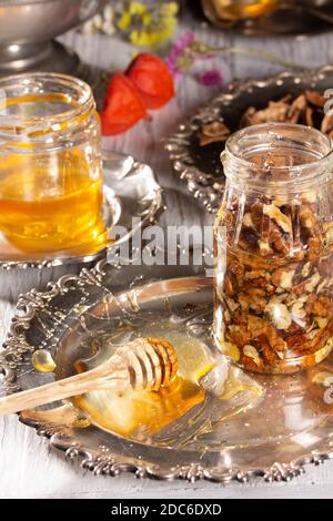 Cucinare un dessert delizioso - noci nel miele. Un vaso riempito di dadi si trova su una piastra di metallo Foto Stock