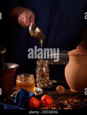 Cucinare un dessert delizioso - noci nel miele. Riempire il vaso con miele Foto Stock