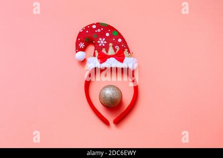 Ritratto decorativo con cappello di Santa e palla di Natale su sfondo rosa. Concetto creativo di Natale minimo. Foto Stock