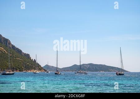 Tavolara, Sardegna / Italia - 2019/07/18: Barche e barche nella pittoresca Tirrenica porti del Mare al largo dell'isola di Isola Tavolara al largo della costa settentrionale di S. Foto Stock