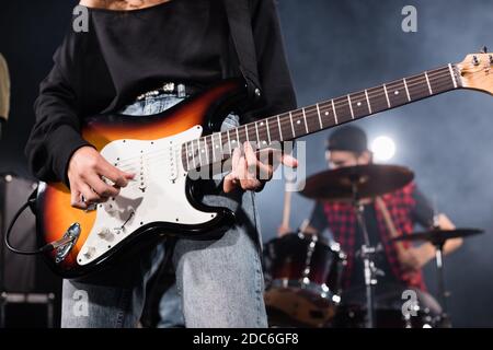 KIEV, UCRAINA - 25 AGOSTO 2020: Musicista femminile che suona la chitarra elettrica con batterista sfocato sullo sfondo Foto Stock