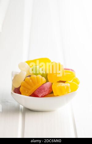 Caramelle di gelatina fruttate colorate in ciotola su tavolo bianco. Foto Stock