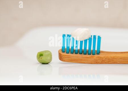 Un primo piano di uno spazzolino da denti in legno con il consigliato dentifricio Foto Stock