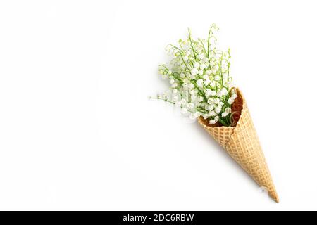 Bouquet di gigli della valle in un cono di cialda su uno sfondo bianco. Cono gelato con fiori primaverili. Biglietto d'auguri. Spazio per la copia, disposizione piatta, v in alto Foto Stock