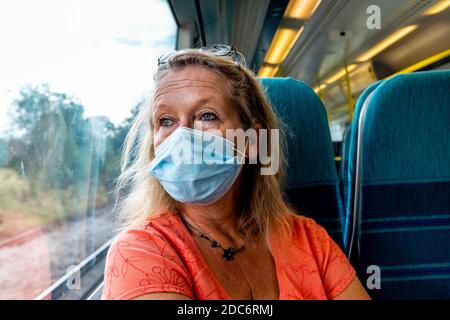 Un viaggiatore femminile su un treno londinese che indossa una maschera protettiva durante il Covid 19 Pandemic, Sussex, UK. Foto Stock