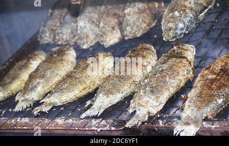 Un primo piano di file di pesce arrosto croccante su un grill Foto Stock