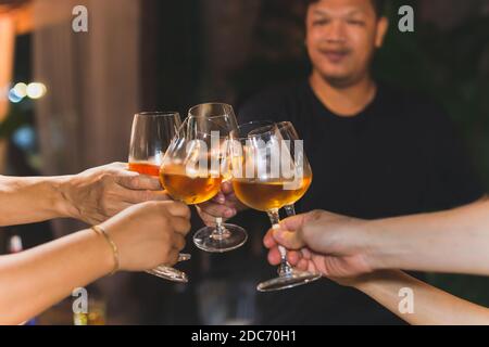 Girato in alta iso con un gruppo di amici poco illuminati che tostano vino bianco. Foto Stock
