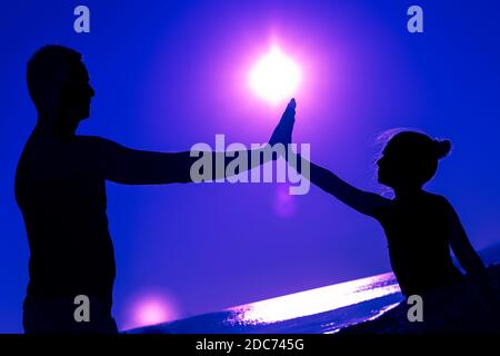 Anapa, Russia-08/16/2020:silhouette di una bambina con suo padre, palme di mani sono sollevate l'una all'altra sullo sfondo di un cosmico blu Foto Stock