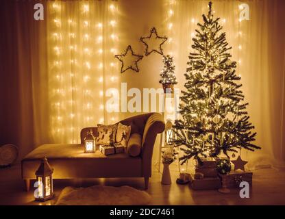 Soggiorno a casa decorato per la vigilia di Natale. Albero di abete rosso di Natale decorato con luci di festa, iciclette e fiocchi di neve, avvolti regali di Natale. Foto Stock