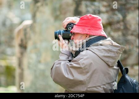 Un uomo anziano usa una macchina fotografica in antiche rovine. Foto Stock