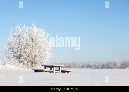 Una panchina nel parco nella neve profonda nel campo Foto Stock