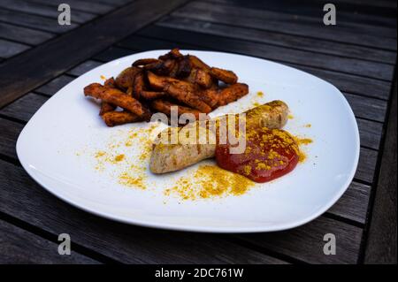 salsiccia di curry vegano con patate e patate dolci spaccate, ketchup con curry in polvere sano da mangiare Foto Stock