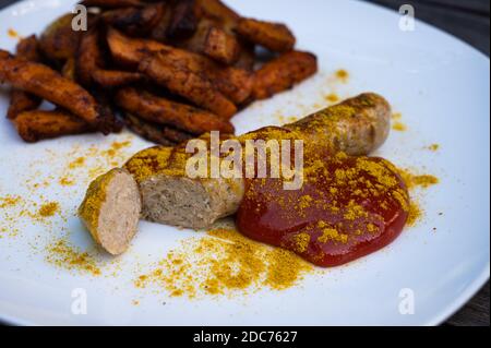 salsiccia di curry vegano con patate e patate dolci spaccate, ketchup con curry in polvere sano da mangiare Foto Stock