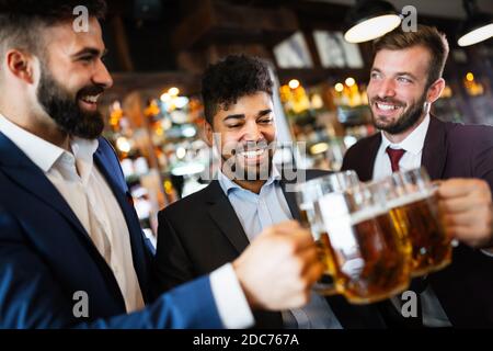 Vecchi amici allegri che si divertono e bevono birra al banco bar nel pub. Foto Stock