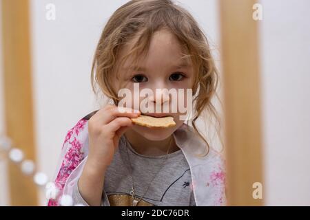 Primo piano di bambina bionda che mangia uno spuntino fatto in casa Foto Stock