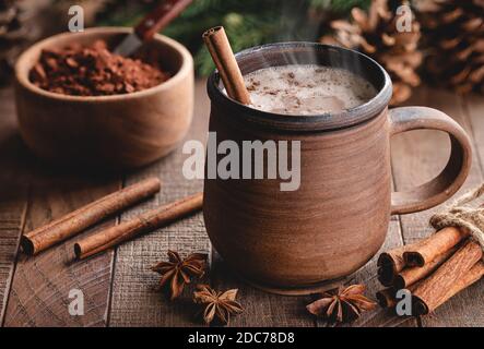 Una tazza di cioccolato caldo al vapore con il bastoncino di cannella su tavolo rustico in legno Foto Stock